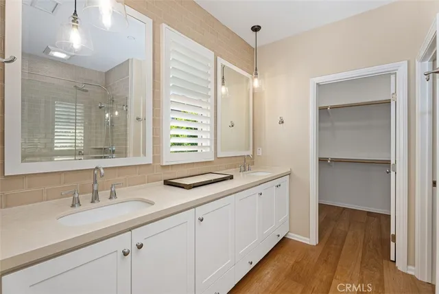 a bathroom with a double vanity sink and mirror with shower