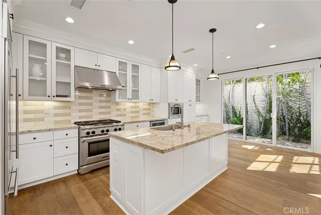 a kitchen with stainless steel appliances granite countertop a stove a sink and a refrigerator