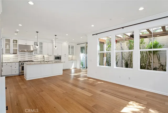 a large white kitchen with kitchen island a large window cabinets and stainless steel appliances