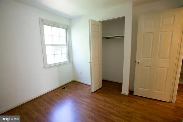an empty room with wooden floor and closet area