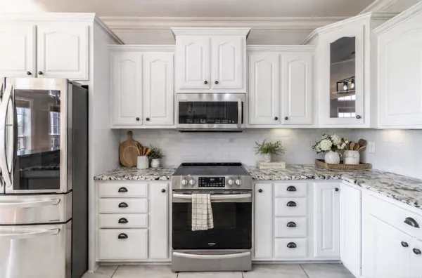 a kitchen with granite countertop white cabinets and stainless steel appliances