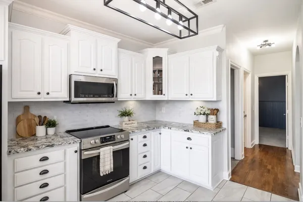 a kitchen with white cabinets and appliances