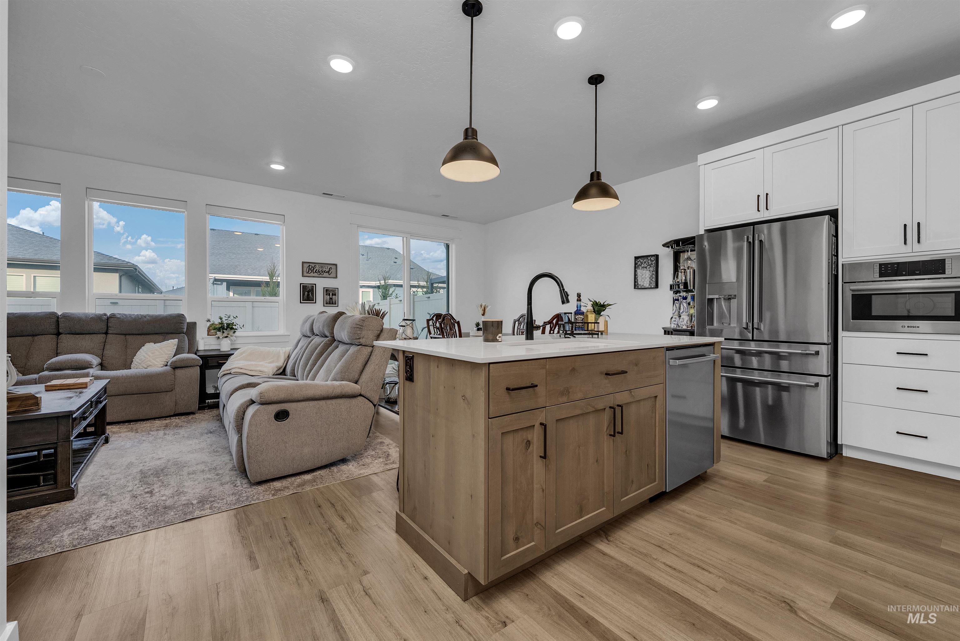4678 West Riva Capri Street Meridian, ID 83646 - Photo 6 of 30 Kitchen with stainless steel appliances, recessed lighting, white cabinetry, hanging light fixtures, and an island with sink