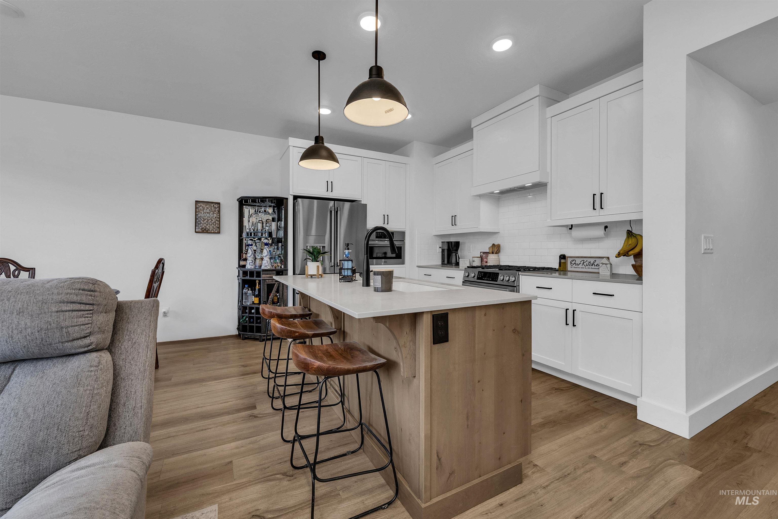 4678 West Riva Capri Street Meridian, ID 83646 - Photo 30 of 30 Kitchen with open floor plan, white cabinets, a kitchen island with sink, a breakfast bar area, and appliances with stainless steel finishes