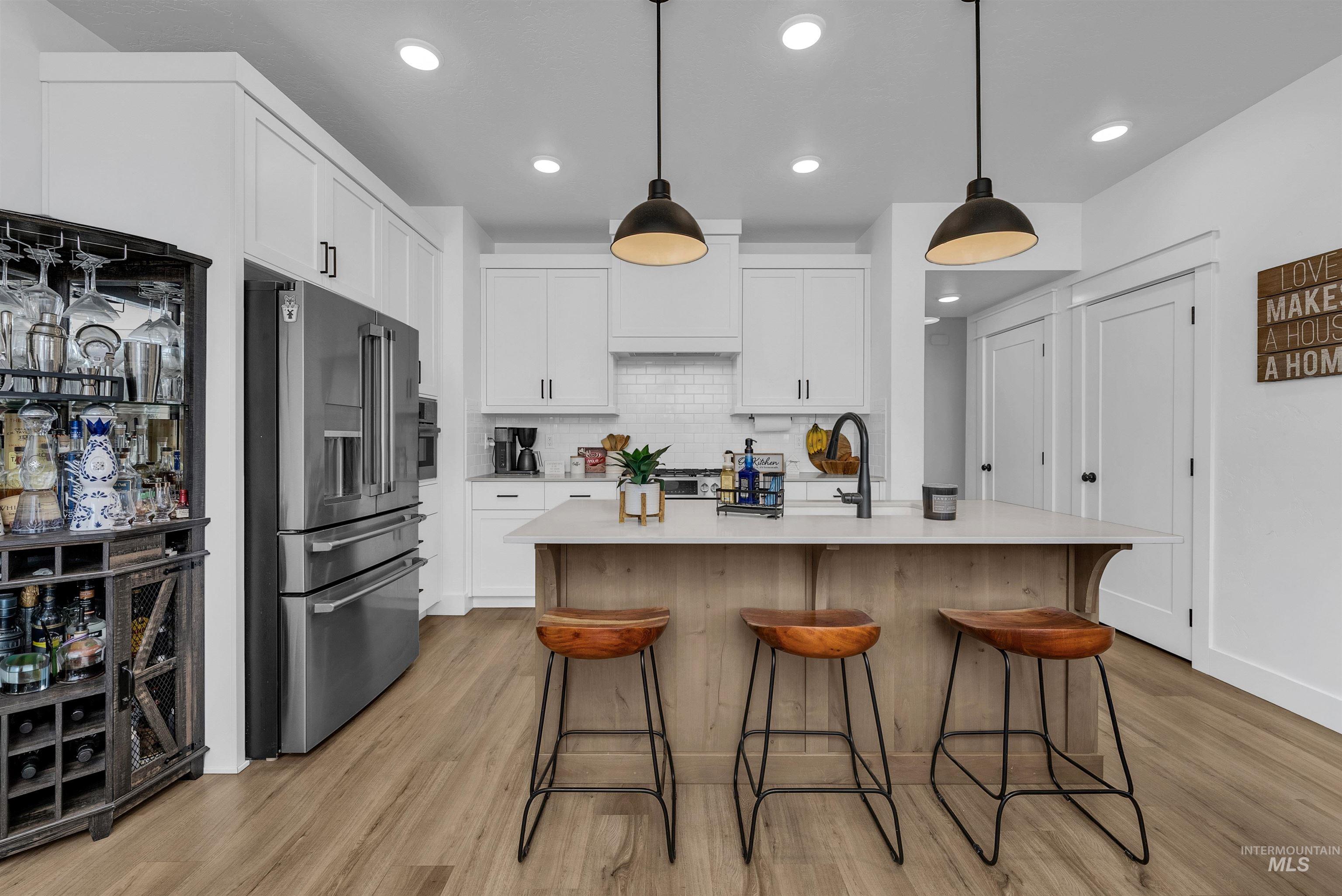 4678 West Riva Capri Street Meridian, ID 83646 - Photo 7 of 30 Kitchen with hanging light fixtures, stainless steel fridge, backsplash, white cabinets, and recessed lighting
