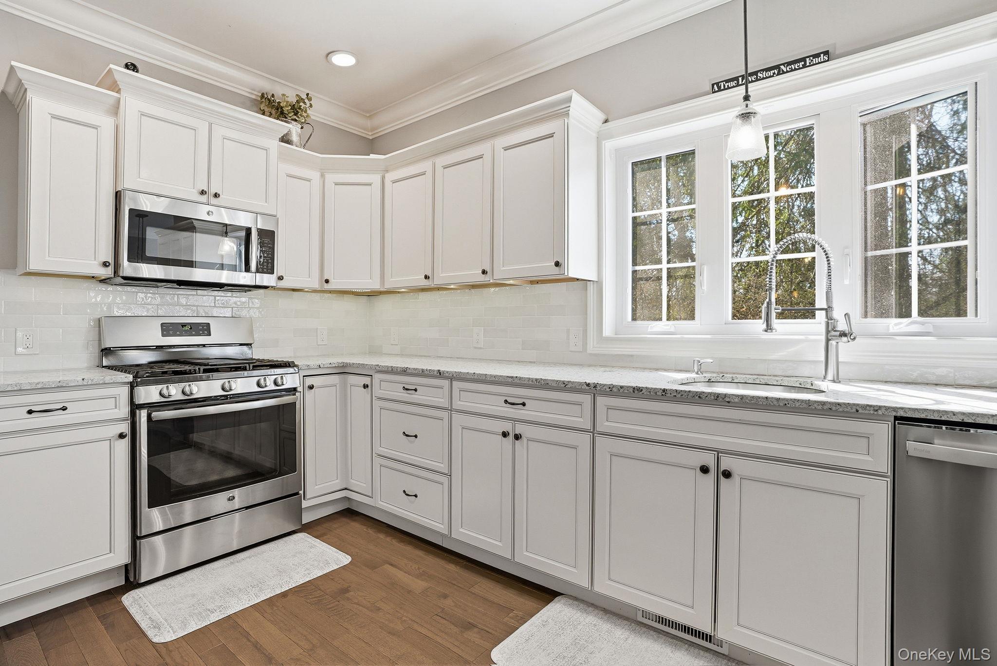 19 Lillian Road Mahopac, NY 10541 - Photo 16 of 50 Kitchen with stainless steel appliances, white cabinets, light stone counters, dark wood finished floors, and crown molding