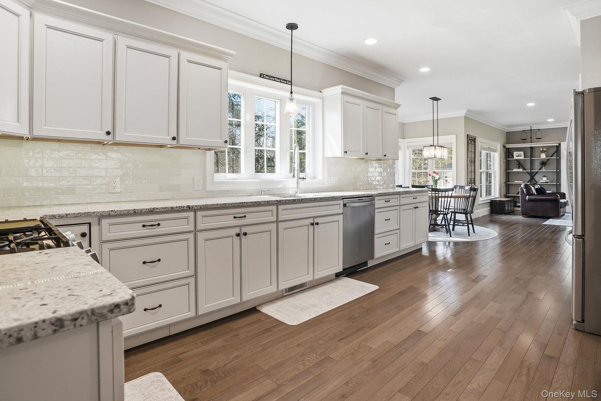 19 Lillian Road Mahopac, NY 10541 - Photo 17 of 50 Kitchen featuring crown molding, white cabinets, dark wood-type flooring, hanging light fixtures, and stainless steel appliances
