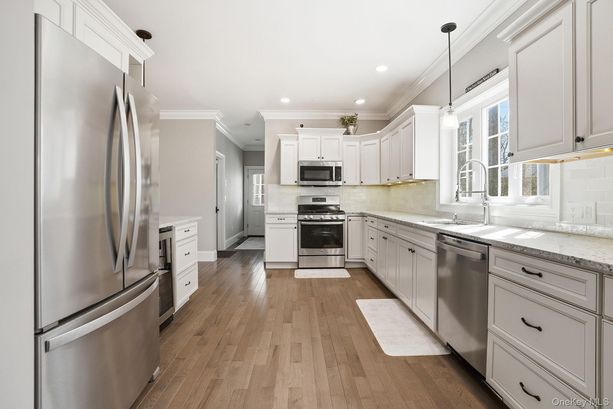 19 Lillian Road Mahopac, NY 10541 - Photo 18 of 50 Kitchen with stainless steel appliances, white cabinetry, dark wood-type flooring, healthy amount of natural light, and crown molding
