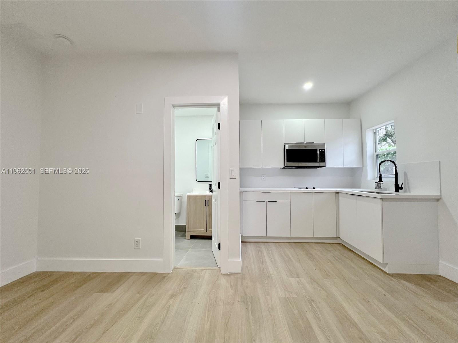 2480 Northwest 96th Street, Unit B Miami, FL 33147 - Photo 3 of 5 a large white kitchen with sink and white cabinets