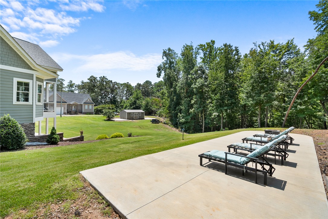 206 James Hare Road Anderson, SC 29626 - Photo 42 of 50 A spacious backyard with a patio provides ample outdoor living space, surrounded by verdant trees and a distant shed.