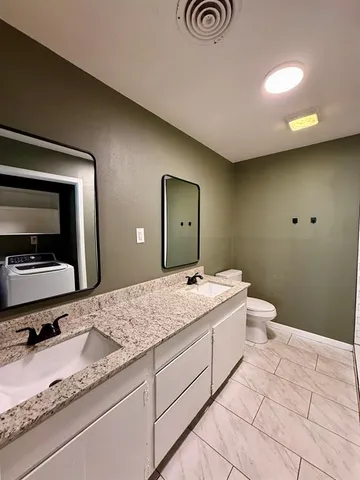 a bathroom with a granite countertop sink a mirror and a toilet