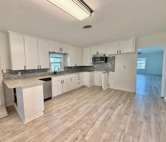 a kitchen with granite countertop white cabinets and white appliances