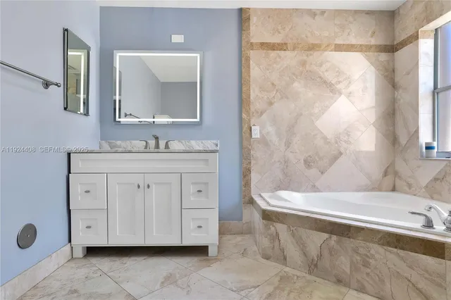 a bathroom with a double vanity sink a mirror and a bathtub