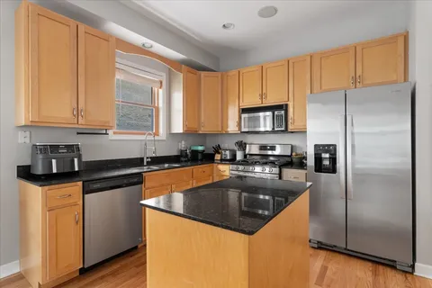 a kitchen with granite countertop stainless steel appliances a refrigerator a sink a stove cabinets and a window