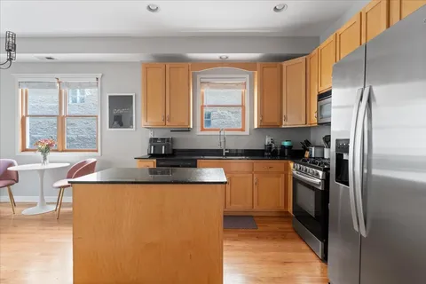 a kitchen with stainless steel appliances granite countertop a refrigerator a sink a stove and white cabinets