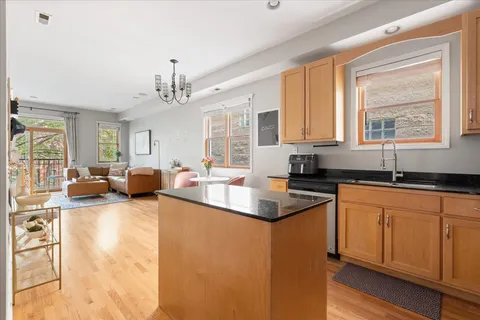 a kitchen with stainless steel appliances granite countertop a sink dishwasher a stove and white cabinets with wooden floor