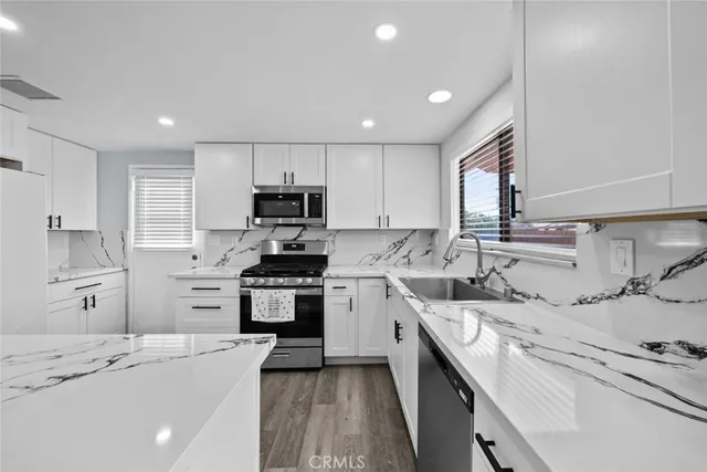 a kitchen with stainless steel appliances a sink stove refrigerator and cabinets