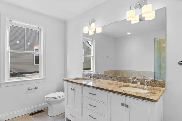 a bathroom with a granite countertop sink a toilet and a mirror