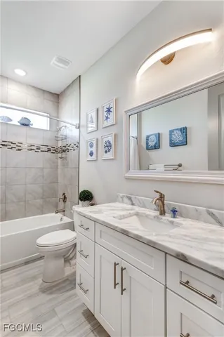 a bathroom with a granite countertop toilet sink and mirror