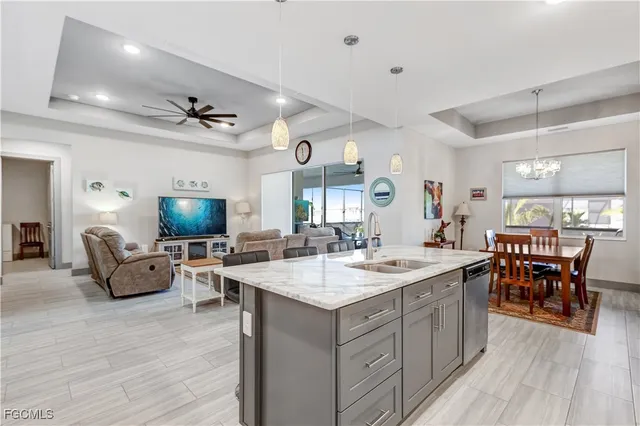 a open kitchen with stainless steel appliances granite countertop a sink dishwasher a stove with a dining table and chairs with wooden floor
