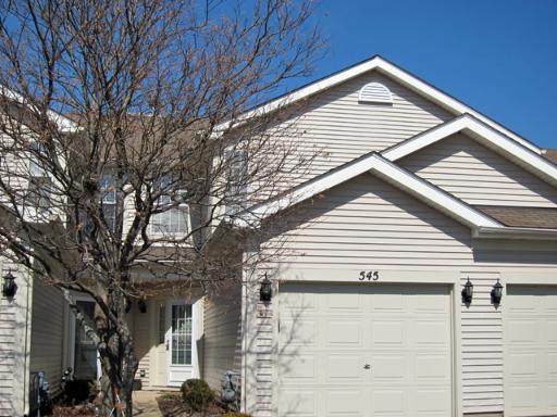a front view of a house with large trees