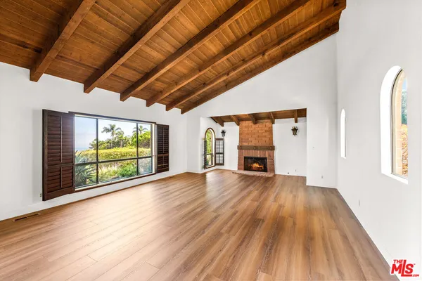a view of an empty room with wooden floor fireplace and a window
