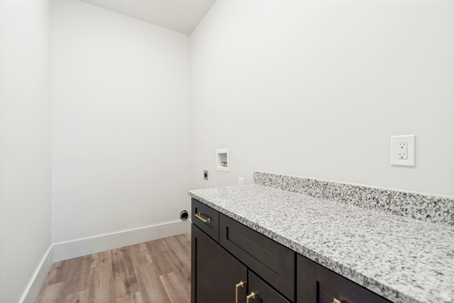 529 North Hvn Drive Mapleton, UT 84664 - Photo 29 of 30 Laundry area featuring wood-finish flooring, white baseboards, and a dark wood-finish cabinet with gold-toned hardware