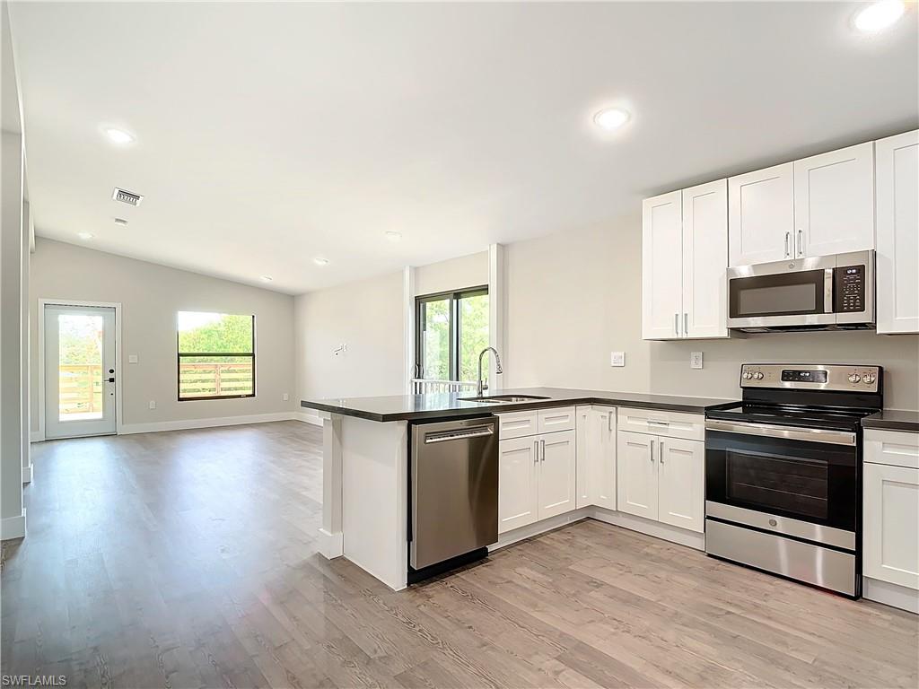 a kitchen with stainless steel appliances granite countertop a stove a sink and a microwave