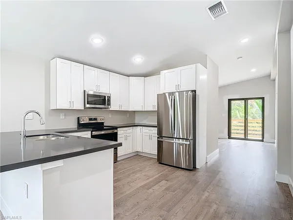 a kitchen with granite countertop stainless steel appliances a refrigerator a sink a stove cabinets and a center island