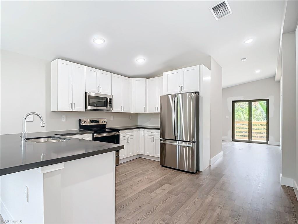 2505 Storter Avenue Naples, FL 34112 - Photo 13 of 49 a kitchen with granite countertop stainless steel appliances a refrigerator a sink a stove cabinets and a center island