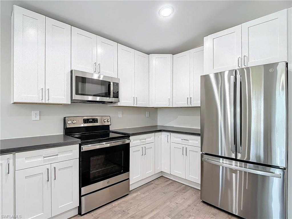 2505 Storter Avenue Naples, FL 34112 - Photo 15 of 49 a kitchen with white cabinets and stainless steel appliances