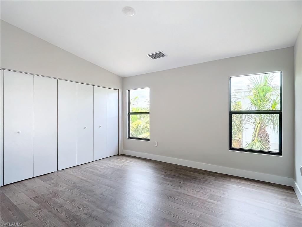 2505 Storter Avenue Naples, FL 34112 - Photo 24 of 49 an empty room with wooden floor and windows