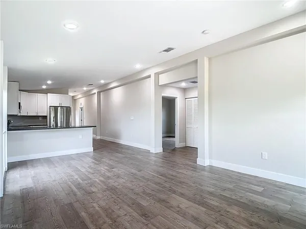 a view of an empty room with kitchen view and a window