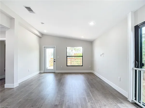 a view of an empty room with wooden floor and a window