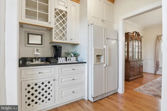 a kitchen with granite countertop a stove a sink and white cabinets with wooden floor next to windows