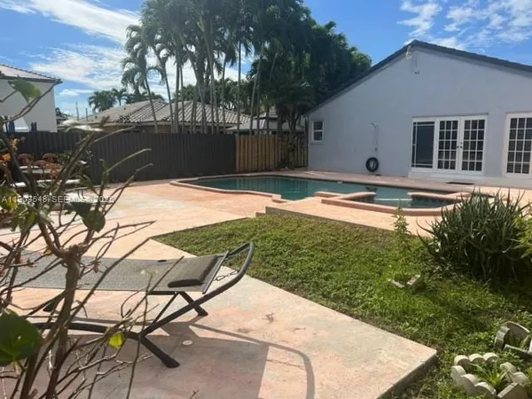 a view of backyard with swimming pool and seating area