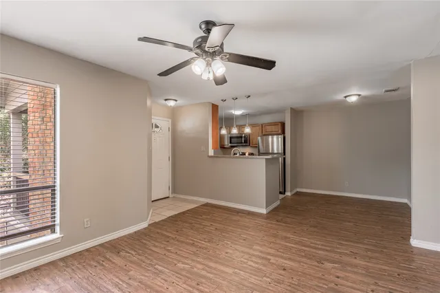 a view of a kitchen with wooden floor a ceiling fan and windows