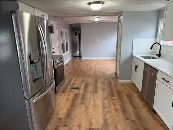 a kitchen with sink a refrigerator and wooden floor