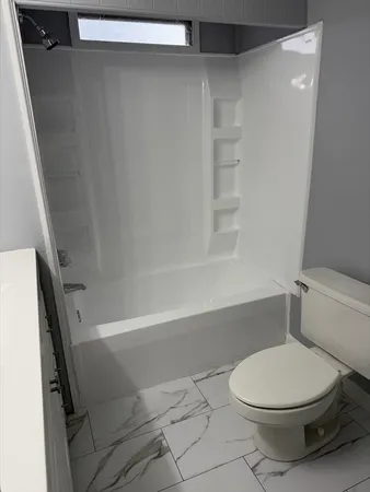 a white toilet sitting next to a bath tub