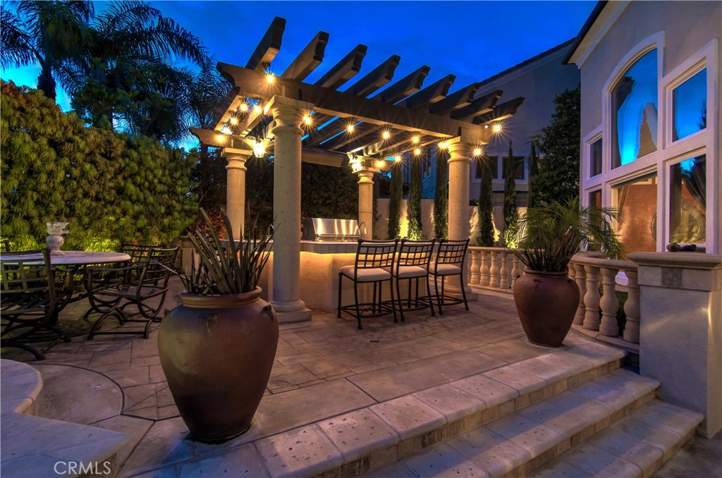 21 Asilomar Road Laguna Niguel, CA 92677 - Photo 26 of 35 a view of a patio with dining table and chairs under an umbrella with a fire pit