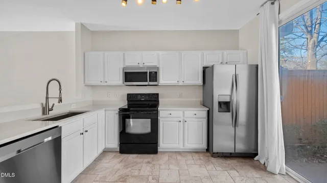 a kitchen with stainless steel appliances a refrigerator sink and white cabinets