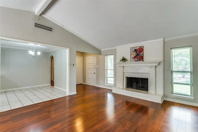 a view of an empty room with wooden floor fireplace and a window