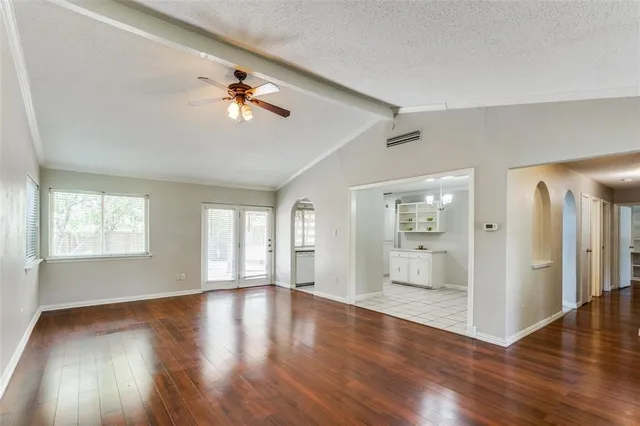 a view of an empty room with window and wooden floor