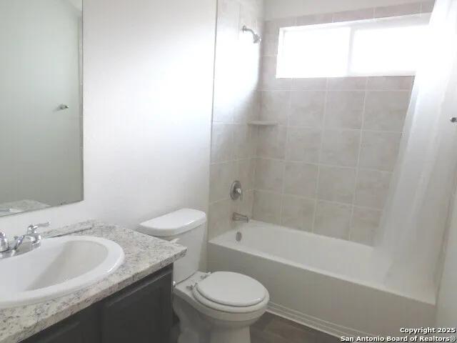 a bathroom with a granite countertop sink a toilet and bathtub