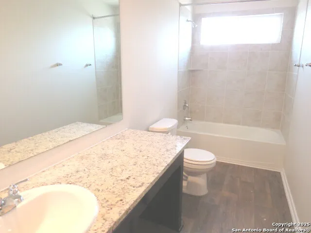 a bathroom with a granite countertop sink a toilet and shower