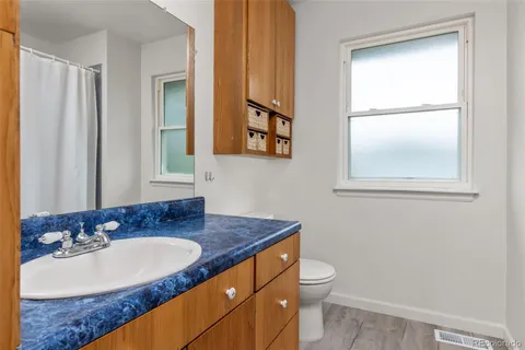 a bathroom with a granite countertop sink toilet and mirror