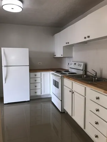 a kitchen with granite countertop white cabinets and white appliances
