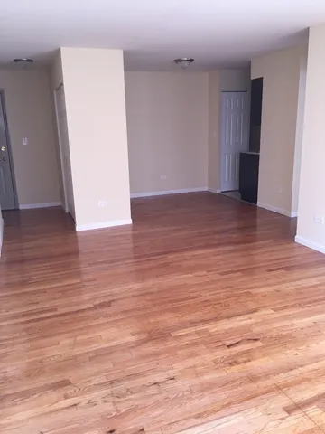 a view of an empty room with wooden floor and closet