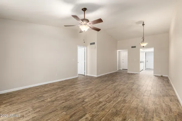 an empty room with wooden floor and chandelier fan