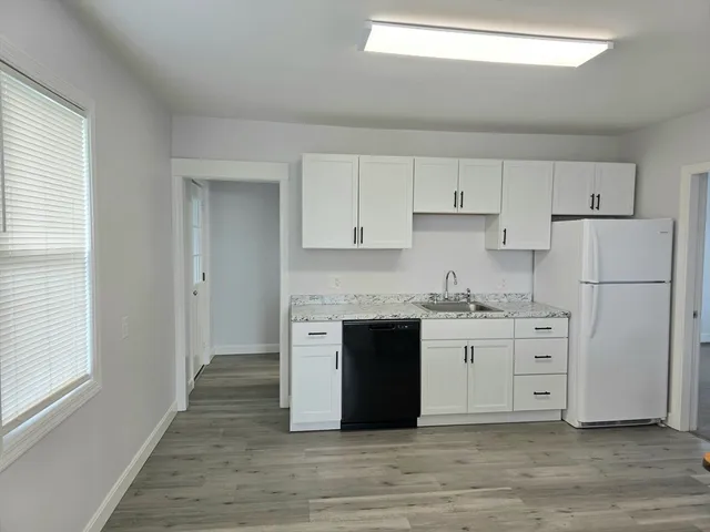 a kitchen with granite countertop a refrigerator stove and white cabinets